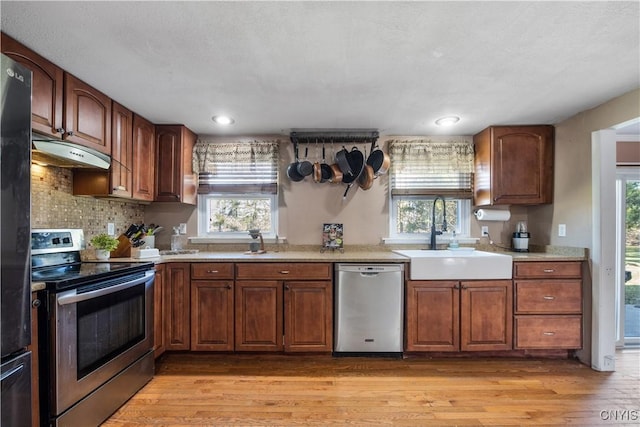 1905 Stump Rd, Skaneateles, NY 13108 - kitchen with light countertops, under cabinet range hood, a sink, light wood-style flooring, and appliances with stainless steel finishes