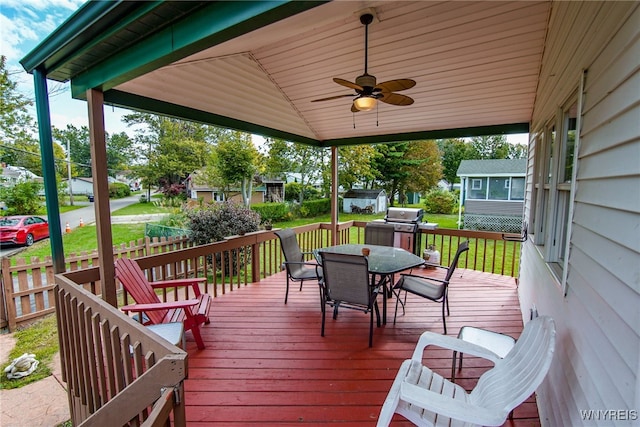 wooden deck featuring outdoor dining area, area for grilling, ceiling fan, and a yard