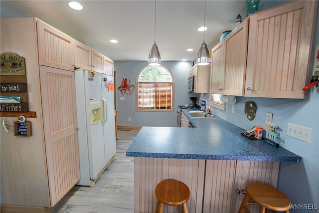 kitchen with a peninsula, appliances with stainless steel finishes, light brown cabinets, light wood-style floors, and a breakfast bar area