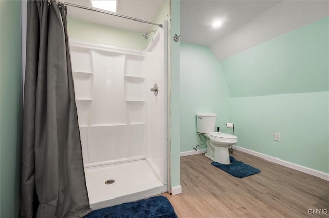 full bath featuring a shower stall, toilet, vaulted ceiling, and wood finished floors