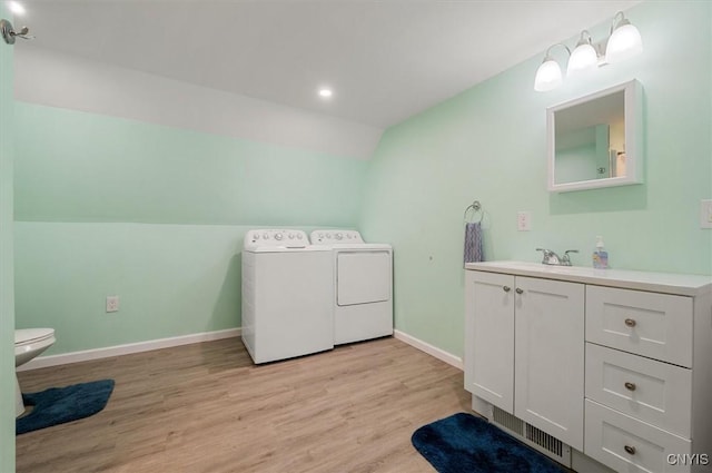 bathroom with vaulted ceiling, vanity, separate washer and dryer, wood finished floors, and baseboards