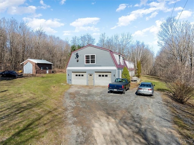 view of side of home featuring a garage, a gambrel roof, driveway, an outbuilding, and a yard