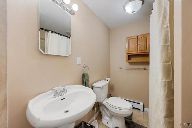 bathroom featuring baseboards, toilet, tile patterned floors, a sink, and a baseboard heating unit