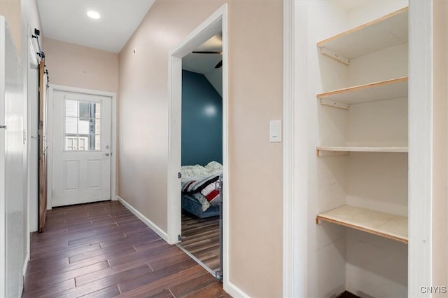 corridor featuring dark wood-type flooring, baseboards, and recessed lighting
