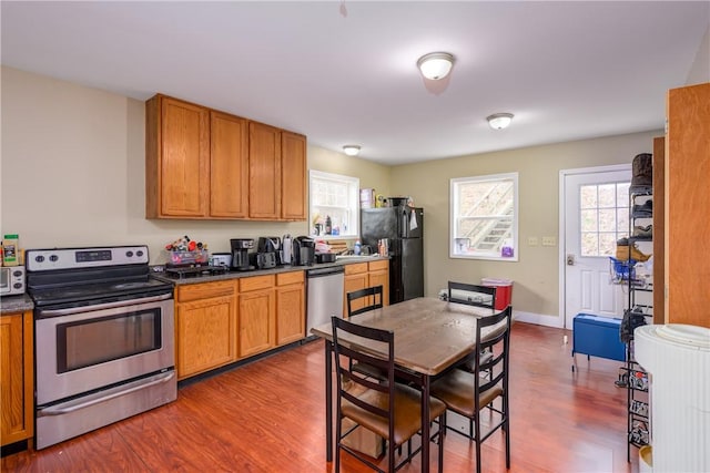 kitchen with plenty of natural light, dark countertops, dark wood finished floors, and appliances with stainless steel finishes