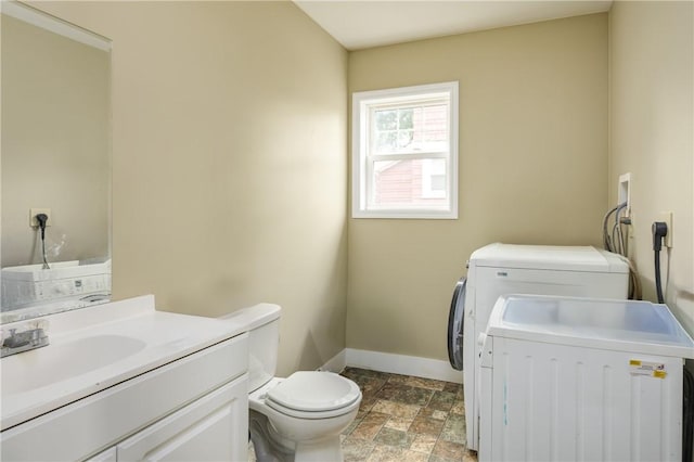 laundry area featuring stone finish floor, baseboards, a sink, washer and dryer, and laundry area