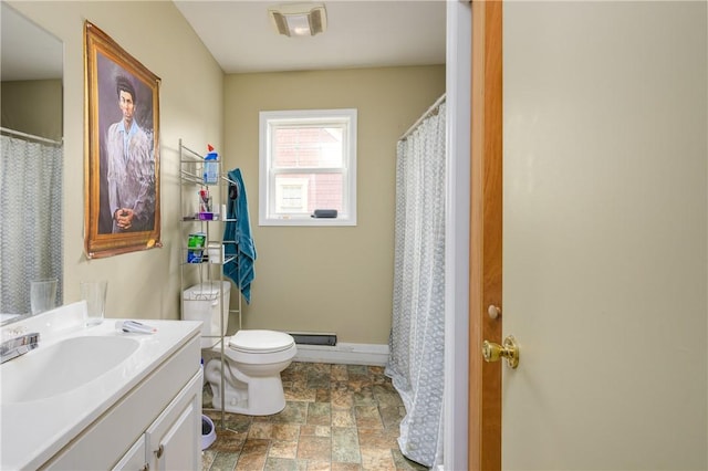 bathroom with a shower with shower curtain, toilet, vanity, stone finish floor, and baseboards