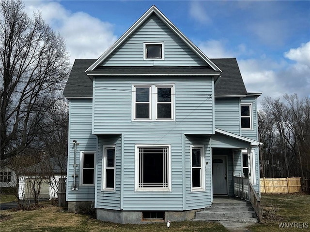 view of front of property with a front lawn, fence, and roof with shingles