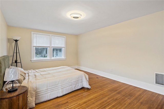 bedroom with baseboards, visible vents, and wood finished floors
