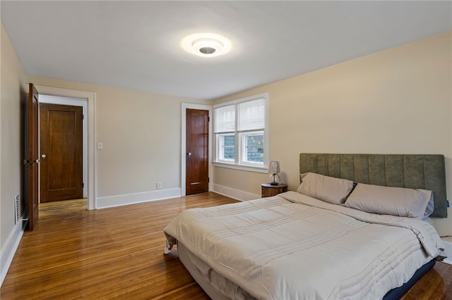 bedroom with visible vents, baseboards, and wood finished floors