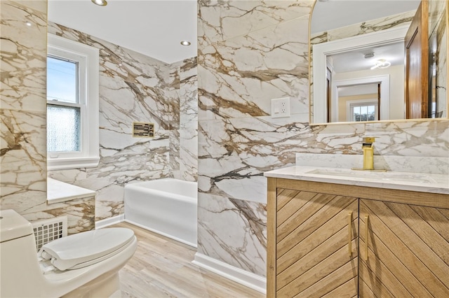 bathroom with a washtub, tile walls, toilet, and vanity