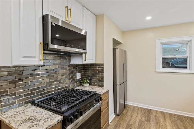 kitchen featuring white cabinetry, tasteful backsplash, light wood-type flooring, stainless steel appliances, and baseboards
