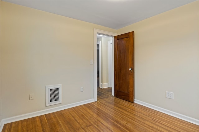unfurnished room featuring baseboards, visible vents, and wood finished floors