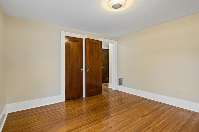unfurnished bedroom featuring baseboards, visible vents, and wood finished floors