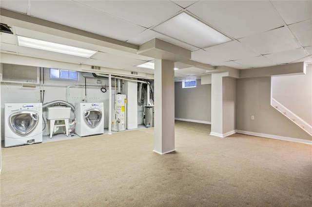 below grade area featuring baseboards, gas water heater, stairway, washer and dryer, and a paneled ceiling