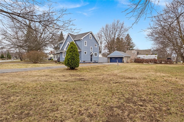 view of property exterior with a lawn, a detached garage, and driveway