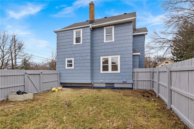 rear view of property with a gate, roof with shingles, a chimney, a fenced backyard, and a lawn