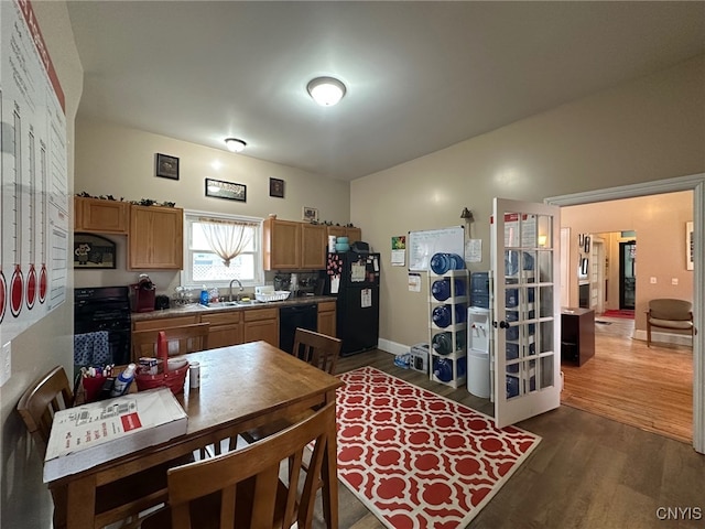 kitchen featuring a sink, baseboards, black appliances, and dark wood-style floors