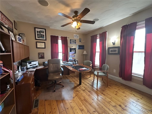 office featuring a wealth of natural light, a ceiling fan, light wood-style floors, and baseboards