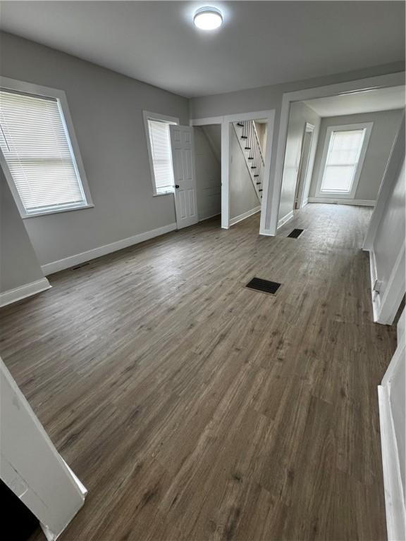 317 W State St, Albion, NY 14411 - unfurnished living room with stairs, plenty of natural light, and dark wood-style flooring