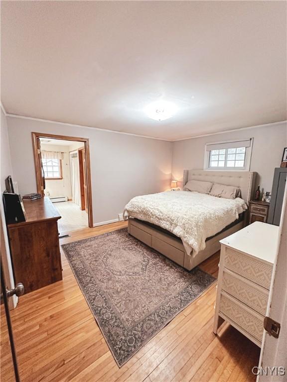 4062 Port St, Richland, NY 13142 - bedroom with light wood finished floors, baseboard heating, and crown molding