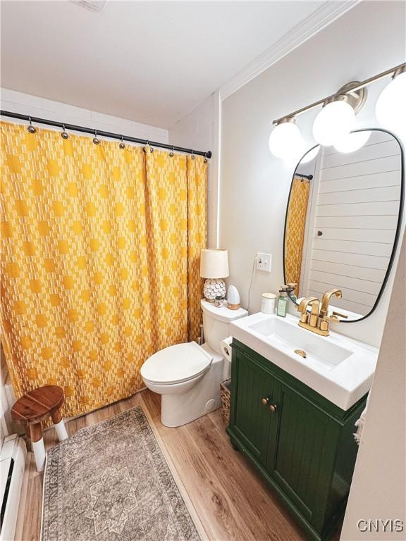 4062 Port St, Richland, NY 13142 - bathroom with wood finished floors, toilet, vanity, a baseboard radiator, and a shower with shower curtain