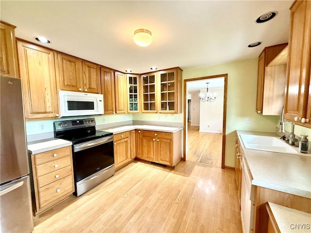 4062 Port St, Richland, NY 13142 - kitchen featuring stainless steel appliances, a sink, light wood-style flooring, a chandelier, and light countertops