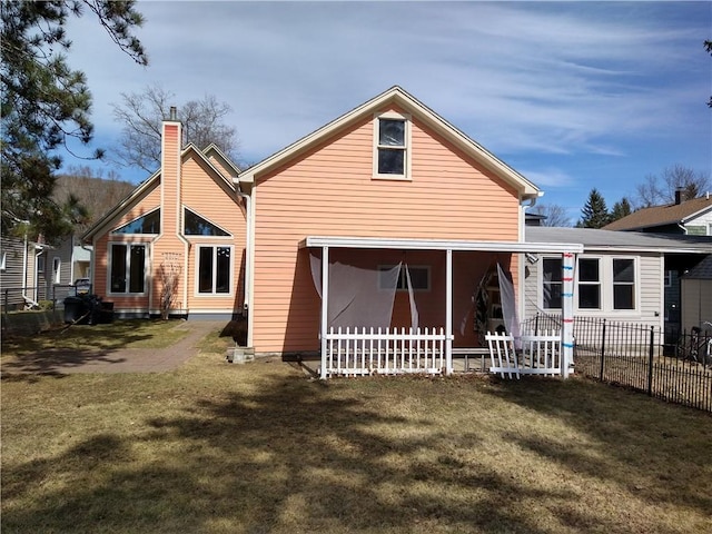 back of property featuring a lawn, a chimney, and fence