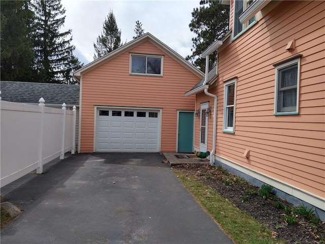 exterior space with fence, a garage, and aphalt driveway