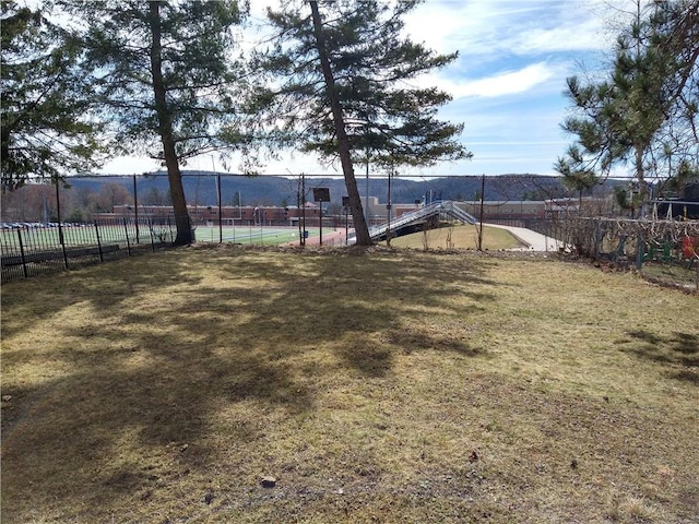 view of yard featuring a tennis court and fence
