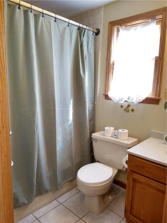 full bath featuring tile patterned floors, shower / bath combination with curtain, toilet, and vanity