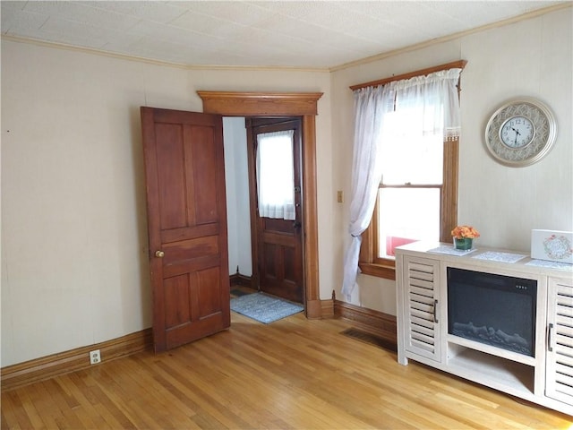 entryway with baseboards, crown molding, and light wood finished floors
