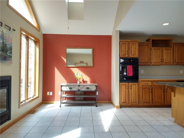 kitchen featuring brown cabinetry, light tile patterned floors, and oven