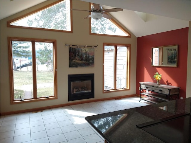 living room with light tile patterned floors, a glass covered fireplace, lofted ceiling, and ceiling fan