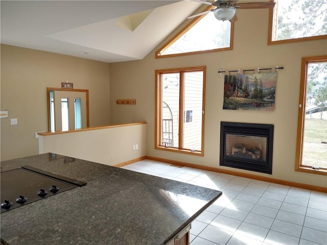 kitchen featuring lofted ceiling, black electric cooktop, a glass covered fireplace, and light tile patterned floors