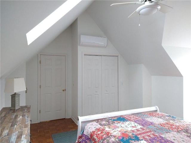 bedroom with a wall unit AC, vaulted ceiling with skylight, a closet, and ceiling fan