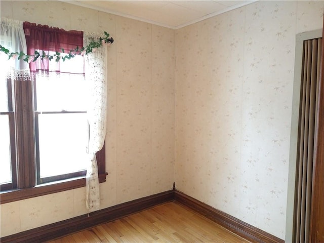 unfurnished room featuring baseboards, wallpapered walls, light wood-style floors, and crown molding