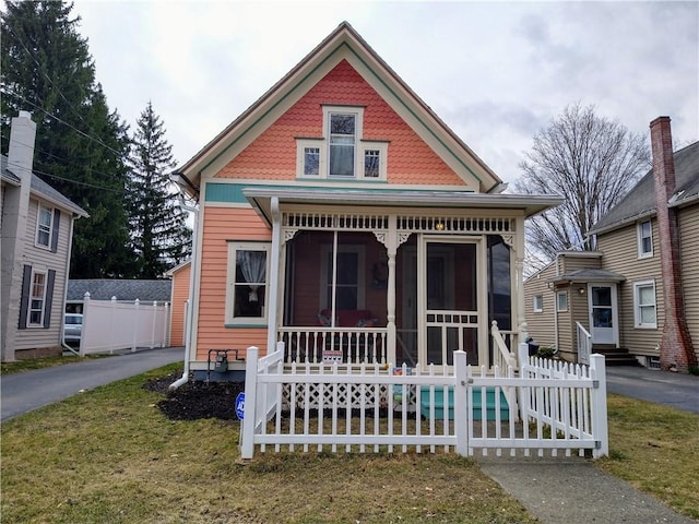 victorian-style house with fence, a porch, and a garage