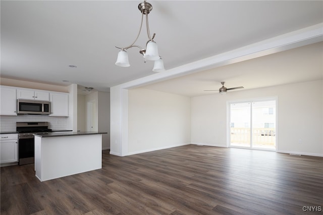kitchen featuring dark countertops, open floor plan, backsplash, dark wood-type flooring, and appliances with stainless steel finishes