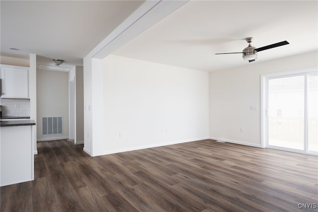 unfurnished living room with dark wood-style floors, baseboards, ceiling fan, and visible vents