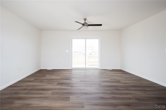 empty room featuring baseboards, a ceiling fan, and dark wood-style floors