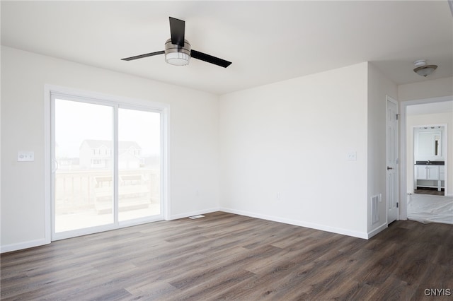 empty room featuring baseboards, visible vents, ceiling fan, and dark wood-style flooring