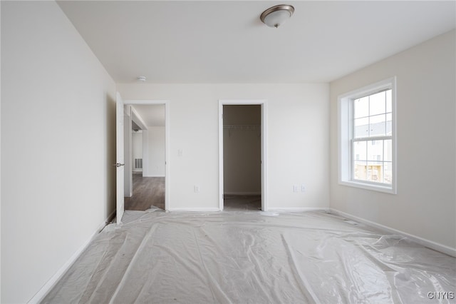 unfurnished bedroom featuring a spacious closet, baseboards, visible vents, and light colored carpet