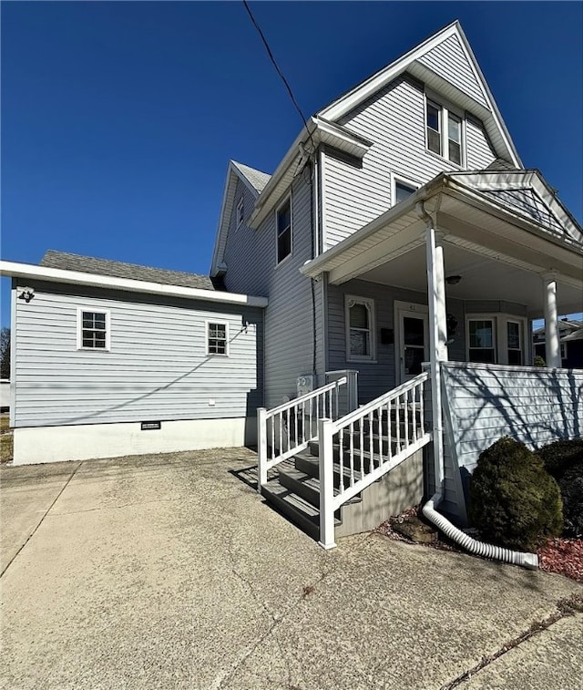 view of side of property with crawl space and covered porch