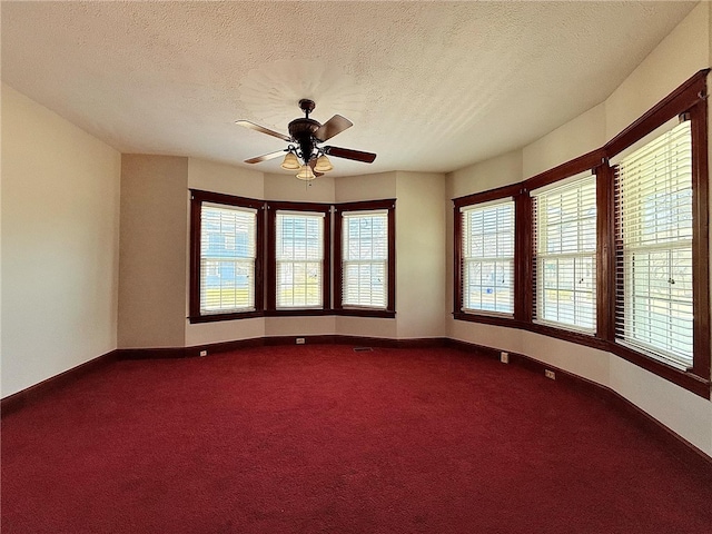 spare room featuring baseboards, ceiling fan, and dark carpet