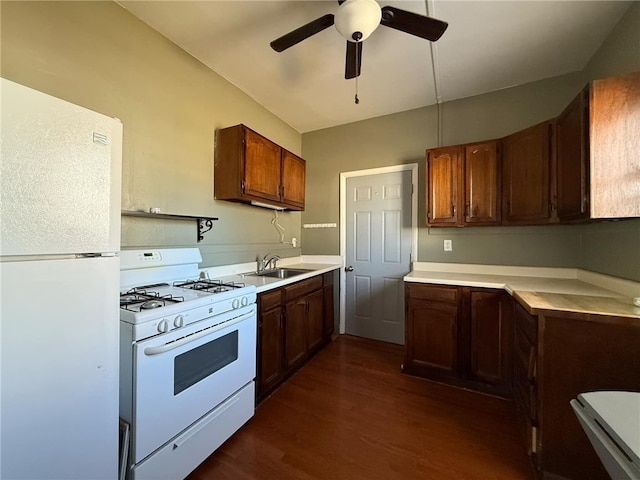 kitchen featuring light countertops, a sink, white appliances, ceiling fan, and dark wood-style flooring