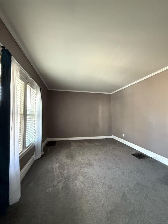 empty room with baseboards, visible vents, crown molding, and dark colored carpet