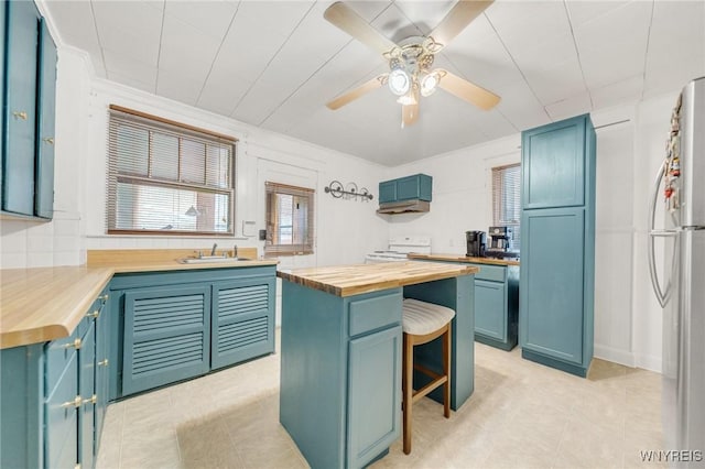 2486 Willow Ave, Niagara Falls, NY 14305 - kitchen featuring freestanding refrigerator, butcher block countertops, a sink, and blue cabinets