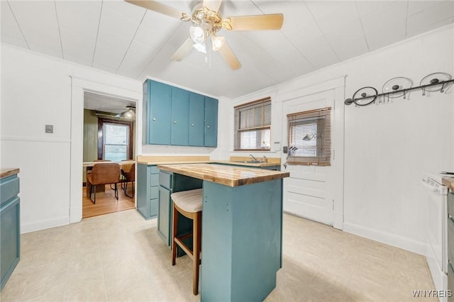 2486 Willow Ave, Niagara Falls, NY 14305 - kitchen with wood counters, ceiling fan, blue cabinetry, a breakfast bar area, and a center island