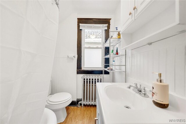 2486 Willow Ave, Niagara Falls, NY 14305 - bathroom featuring radiator heating unit, toilet, vanity, and wood finished floors
